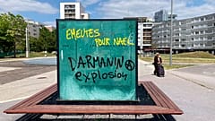 Graffiti reads "Riots for Nahel, Explosion for Darmanin," referring to French Interior Minister Gerald Darmanin, on an urban furniture on July 2 in the Paris suburb Nanterre.