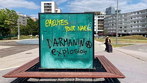 Graffiti reads "Riots for Nahel, Explosion for Darmanin," referring to French Interior Minister Gerald Darmanin, on an urban furniture on July 2 in the Paris suburb Nanterre.