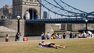 People are seen sunbathing at Tower Bridge area during the June heatwave.