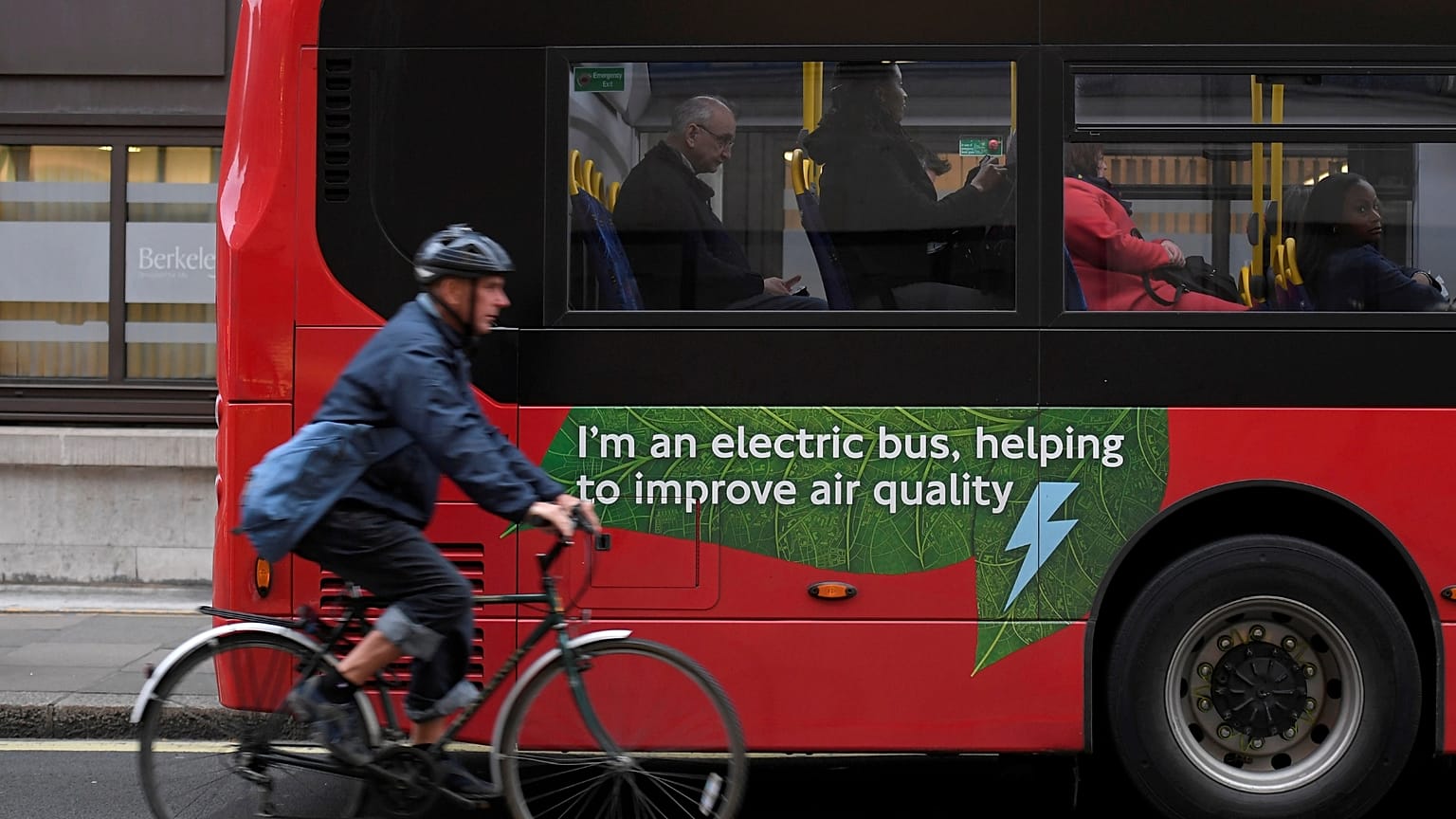 A cyclist rides past an electric public bus in London. 