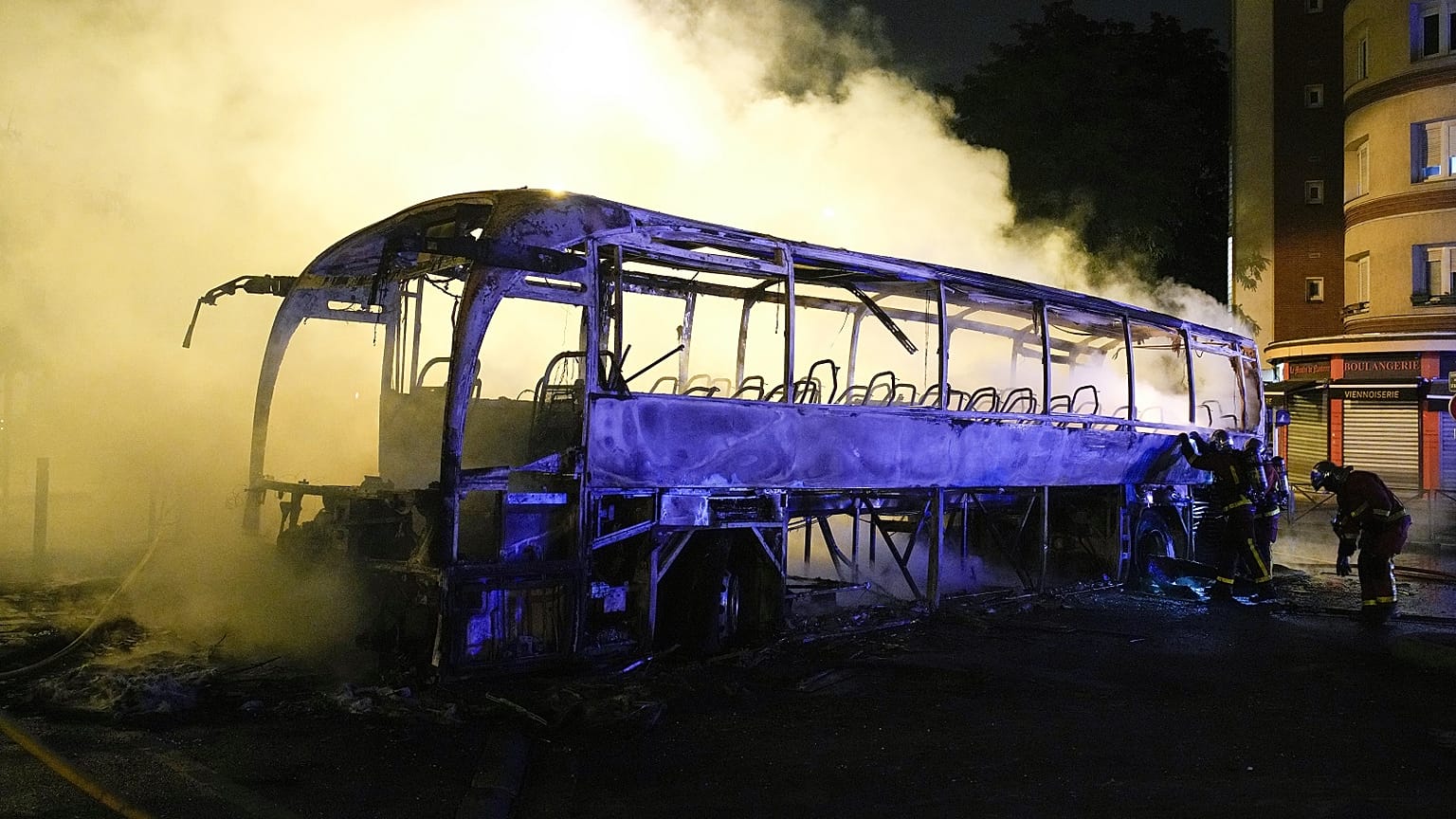 I vigili del fuoco usano una manichetta d'acqua su un autobus bruciato a Nanterre, fuori Parigi, Francia, 1 luglio 2023.