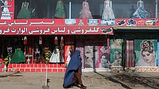 Afgán nő sétál Kabulban egy butik és egy szépségszalon előtt 2015-ben