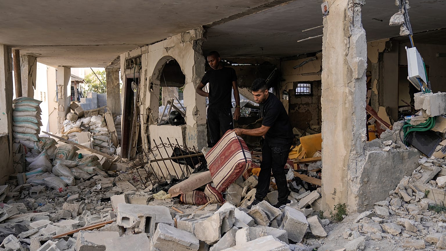 Palestinianos inspecionam casa danificada no campo de refugiados de Jenin, na Cisjordânia, esta quarta-feira.
