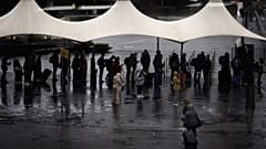 Amsterdam'daki Schiphol Havaalanı'nda şiddetli fırtınanın neden olduğu yağmurdan korunmaya çalışan vatandaşlar