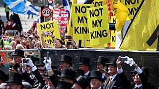 Anti-monarchy protesters hold placards near St Giles' Cathedral in Edinburgh as Charles III arrives for a coronation celebration