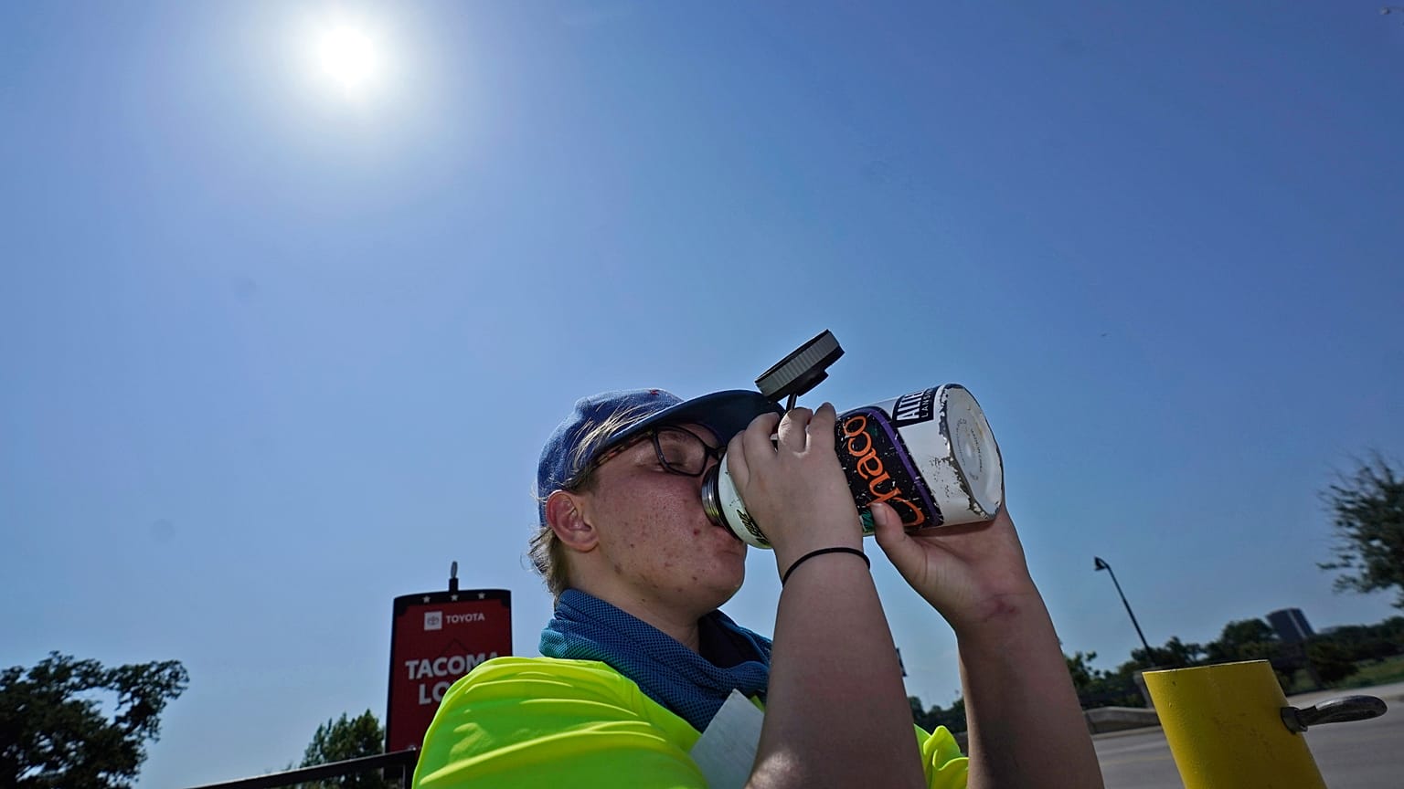Jennifer Michener boit de l'eau en travaillant sous un soleil de plomb dans un parking à Arlington, Texas, lundi 26 juin 2023.