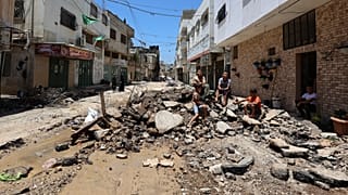 فلسطينيون يجلسون وسط الأنقاض على طول شارع في مخيم جنين للاجئين بالضفة الغربية المحتلة. 2023/07/06