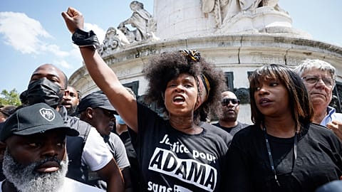 Woman raises her clenched fist in the air at the commemorative rally for Adama Traoré