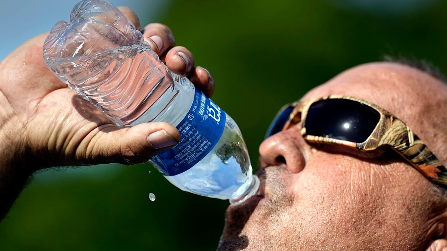 Robert Harris boit de l'eau tout en faisant une pause après avoir creusé des trous de poteaux de clôture, le mardi 27 juin 2023, à Houston aux Etats-Unis
