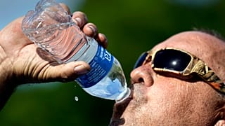 Robert Harris boit de l'eau tout en faisant une pause après avoir creusé des trous de poteaux de clôture, le mardi 27 juin 2023, à Houston aux Etats-Unis