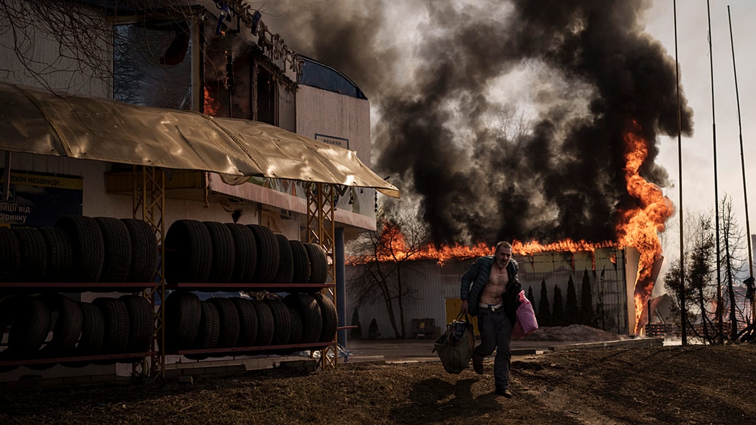 A man runs while recovering items from a burning shop following a Russian attack in Kharkiv, Ukraine, Friday, March 25, 2022. 