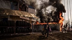 A man runs while recovering items from a burning shop following a Russian attack in Kharkiv, Ukraine, Friday, March 25, 2022. 