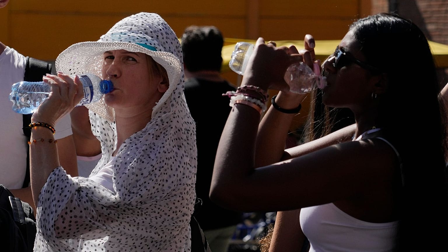 Des touristes sirotent de l'eau fraîche alors qu'ils s'abritent d'une chaude après-midi ensoleillée près du Colisée de Rome, le 5 juillet 2023\. 