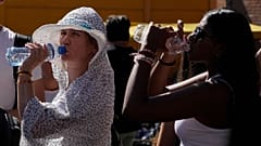 Turistas bebem água fria enquanto se abrigam de uma tarde de sol quente perto do Coliseu de Roma, a 5 de julho de 2023. 