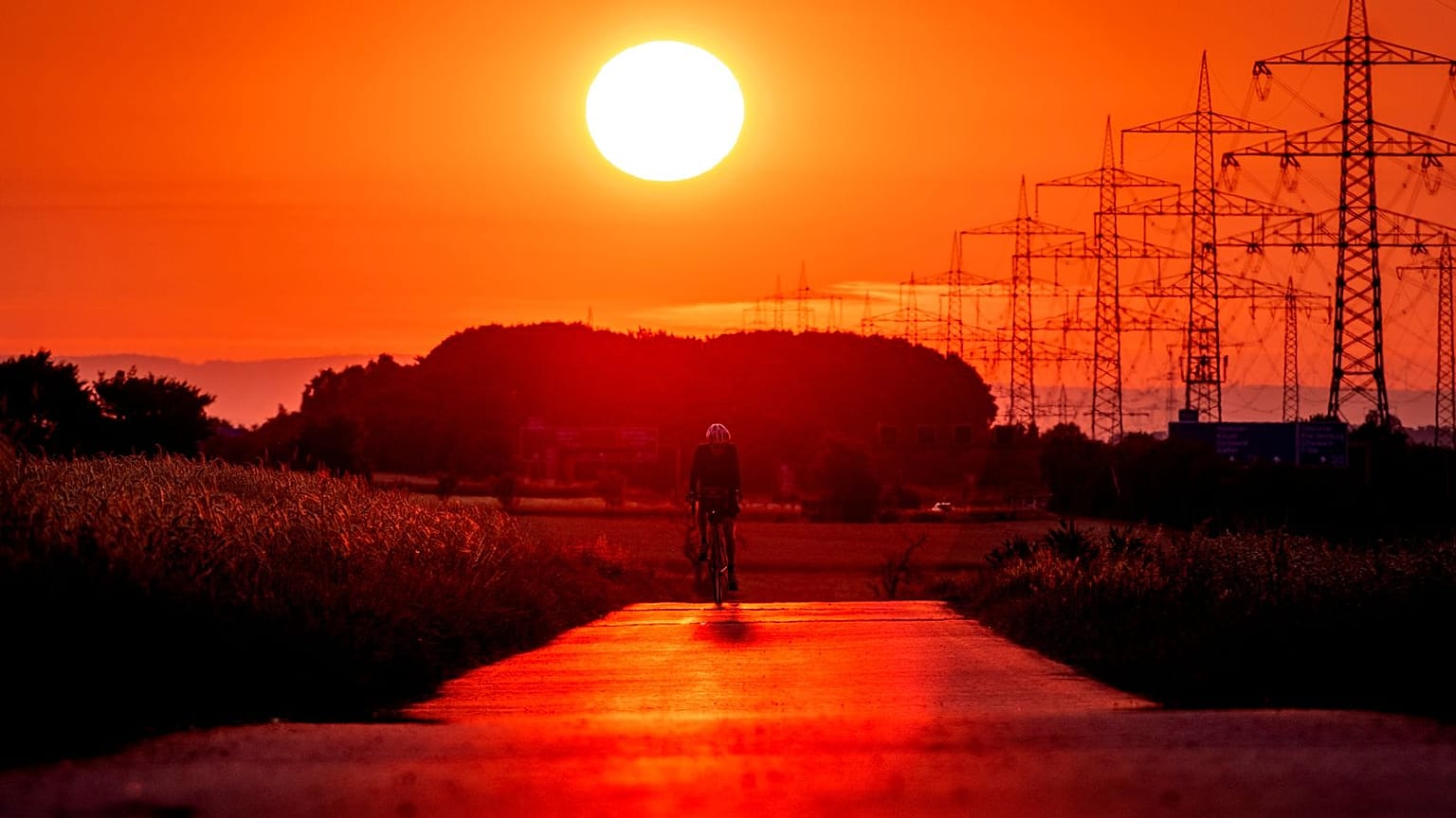 Ein Mann fährt mit seinem Fahrrad auf einer kleinen Straße am Stadtrand von Frankfurt, 9. Juli 2023  