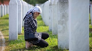 A Bosnian muslim woman mourns next to the grave of her relative, victim of the Srebrenica genocide, at the memorial centre in Potocari, Bosnia.