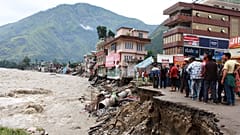 Menschen stehen an einer Straße, die vom Fluss Beas weggespült wurde, der aufgrund starker Regenfälle im Distrikt Kullu im indischen Bundesstaat Himachal Pradesh gestiegen ist