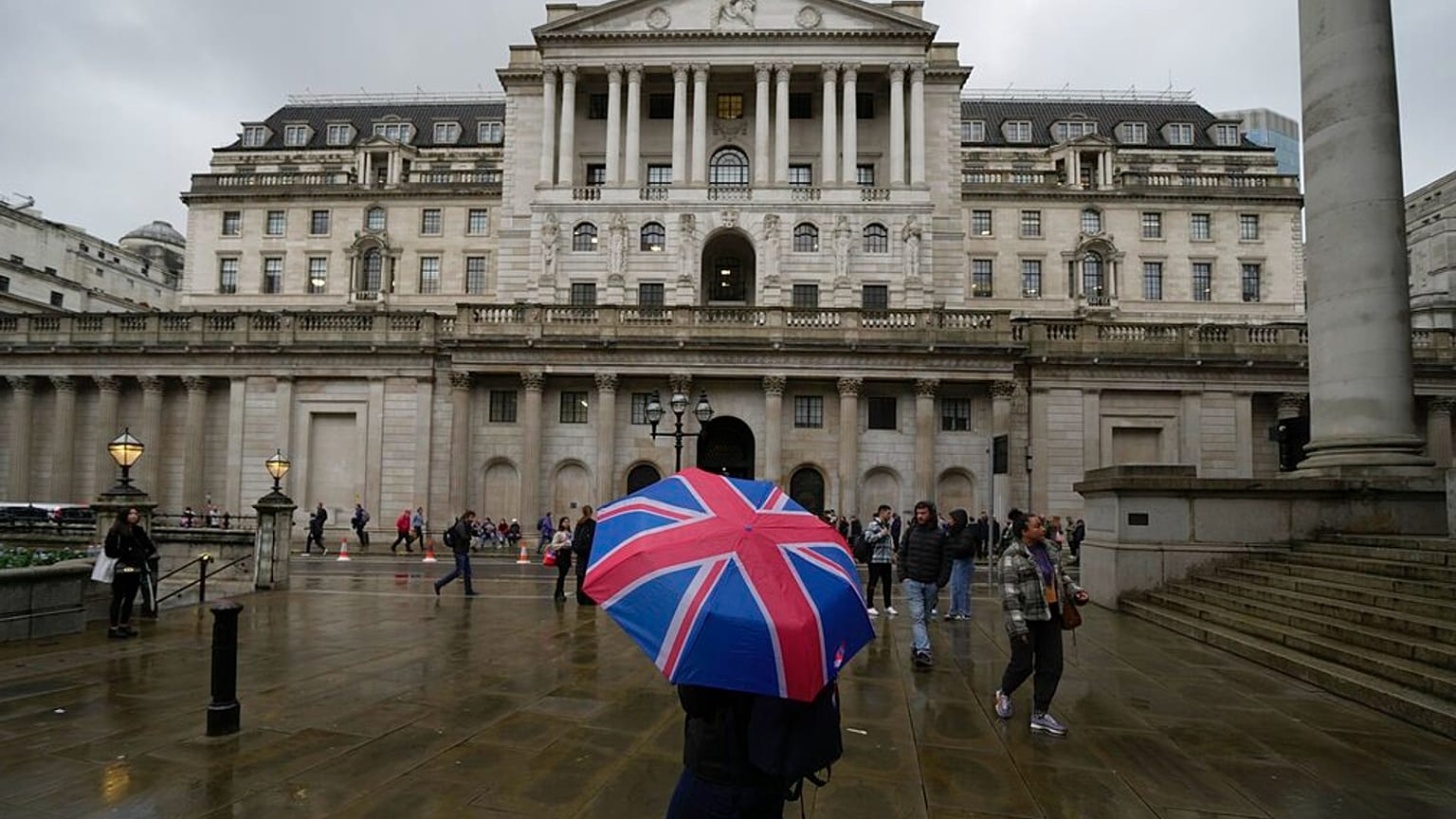 A woman with an umbrella stands in front of the Bank of England, at the financial district in London, Thursday, Nov. 3, 2022.