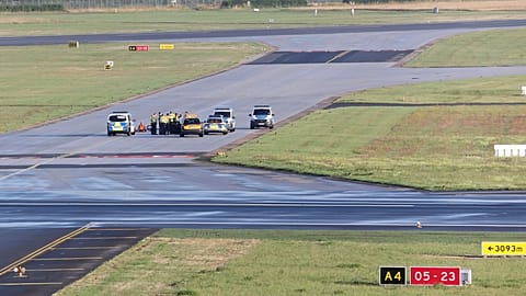 Security personnel and police officers stand near climate activists from the group Last Generation who stuck themselves to tarmac at Hamburg Airport, Germany, July 13, 2023.