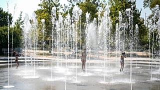 Des enfants jouent dans une fontaine d'eau pendant une vague de chaleur, au centre culturel de la fondation Stavros Niarchos à Athènes.; le 13 juillet 2023