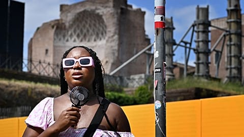 A woman cools off with a mini fan in Rome, on July 14, 2023, as Italy is hit by a heatwave.