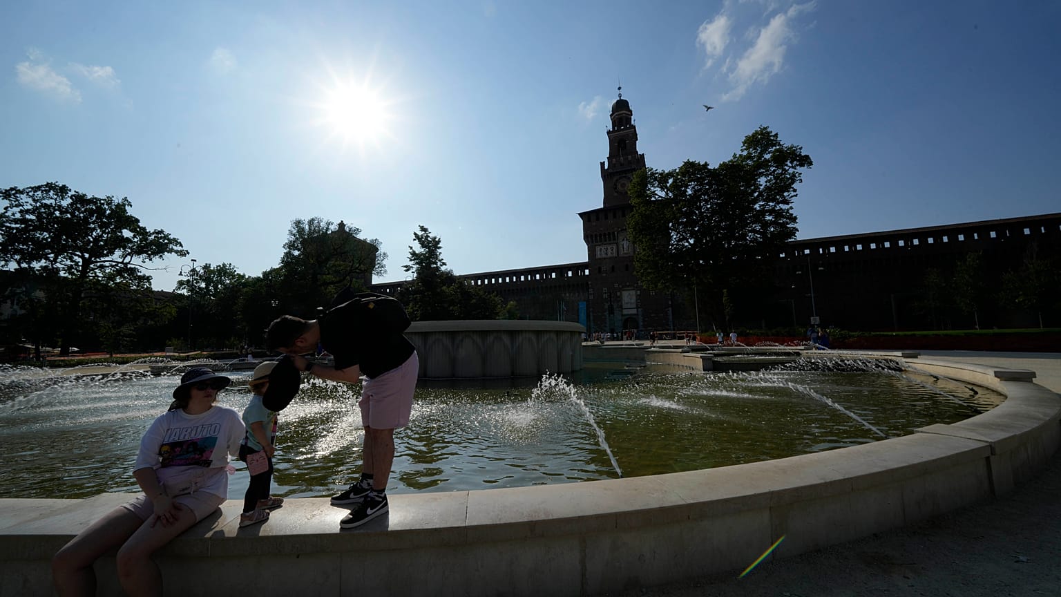 Turistas refrescam-se numa fonte pública no Castelo Sforzesco, em Milão, Itália, sábado, 15 de julho de 2023. 