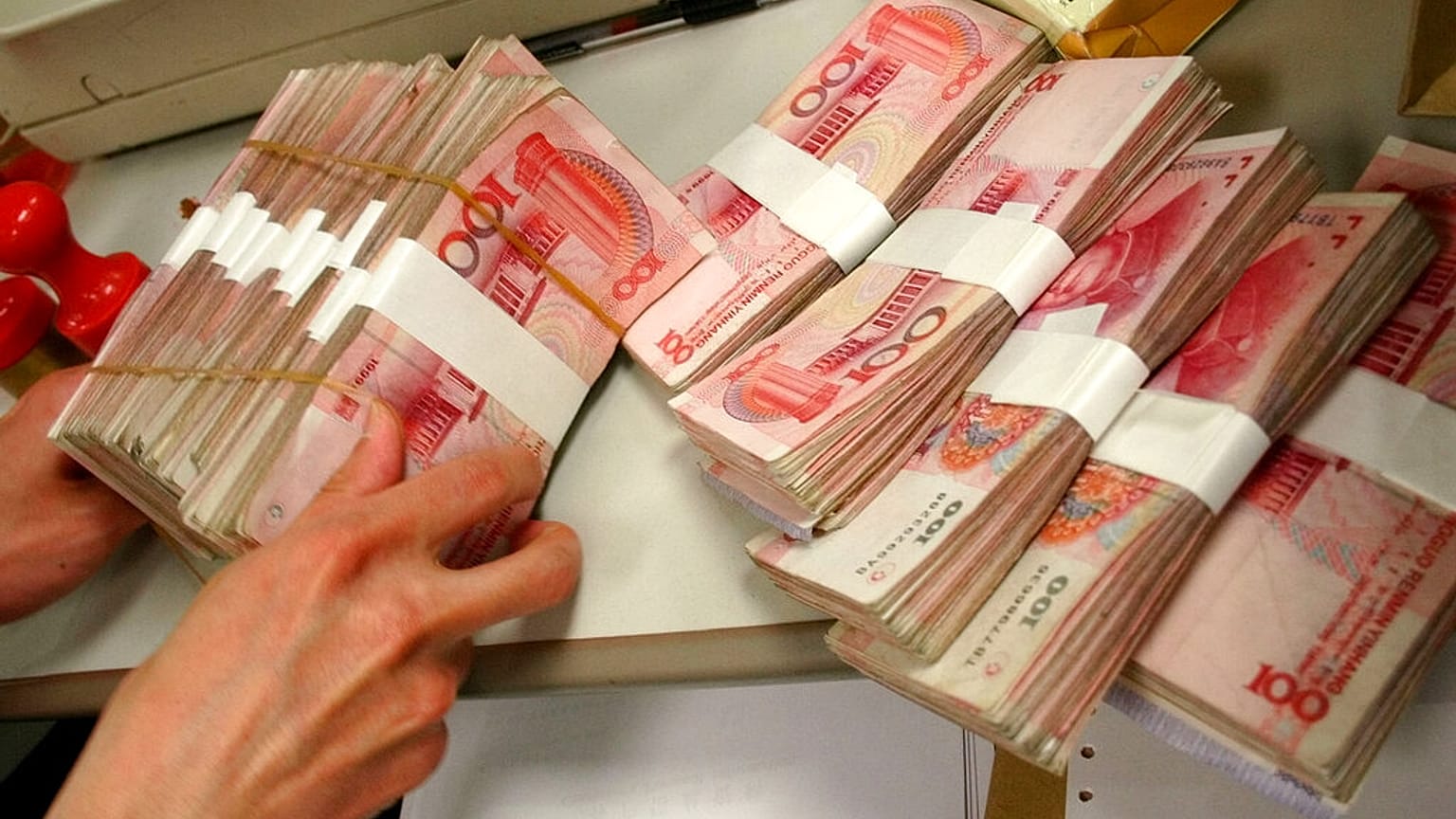 صورة من الارشيف- صراف يتعامل مع اليوان الصيني في أحد البنوك في بكين.