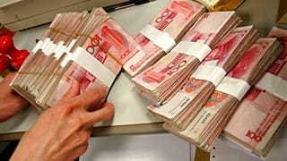 صورة من الارشيف- صراف يتعامل مع اليوان الصيني في أحد البنوك في بكين.