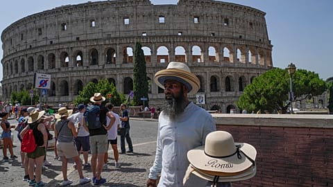 A street vendor walks with hats in front of the Colosseum in Rome