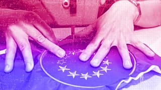 A seamstress stitching starts on a European flag patch in Budapest, April 2003
