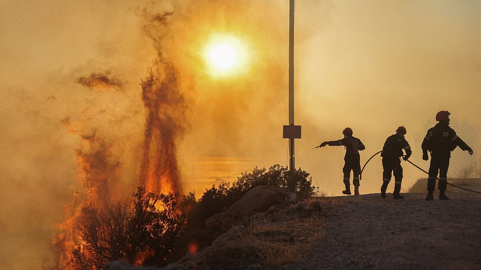 Os bombeiros tentam extinguir um incêndio florestal que está a arder em Saronida, perto de Atenas, na Grécia, a 17 de julho de 2023\. 