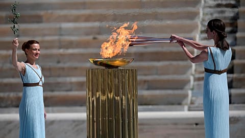Greek actress Xanthi Georgiou dressed as an ancient Greek high priestess lights the Olympic torch as choreographer Artemis Ignatiou looks on during the olympic flame handover.