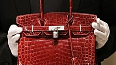 A employee holds a 129,000 USD crocodile Hermes Birkin Bag for the press to see during a private opening for the new Hermes store on Wall Street in New York 21 June 2007.