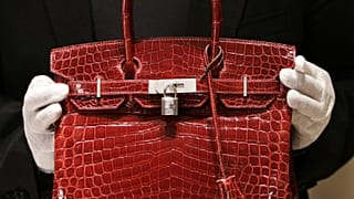 A employee holds a 129,000 USD crocodile Hermes Birkin Bag for the press to see during a private opening for the new Hermes store on Wall Street in New York 21 June 2007.
