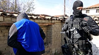 FILE - a police officer guards a detained person during a police raid in Sofia, Bulgaria in 2018.