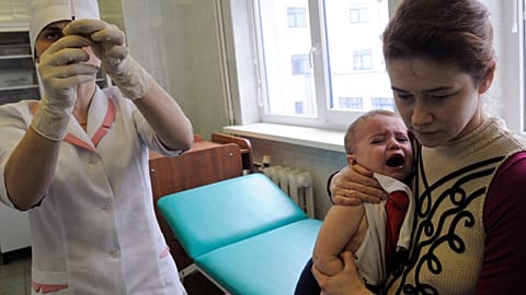 A medical worker prepares to administer a vaccine to 16 month old Yaroslav who is being held my his mother Oksana in Ukraine, 2009.