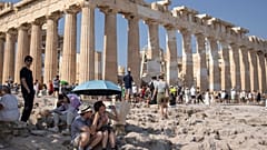 Tourist sit in front of the five century BC Parthenon temple at the Acropolis hill during a heatwave, Thursday 13 July 2023.