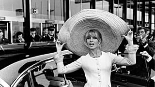 French actress Brigitte Bardot poses with a huge sombrero she brought back from Mexico, as she arrives at Orly Airport in Paris, France, on May 27, 1965.