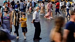A man wearing a face mask to protect against the spread of coronavirus pauses as people walk along a street in downtown Barcelona, Spain, July 3, 2021.