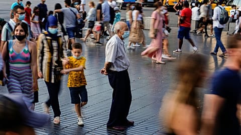 A man wearing a face mask to protect against the spread of coronavirus pauses as people walk along a street in downtown Barcelona, Spain, July 3, 2021.