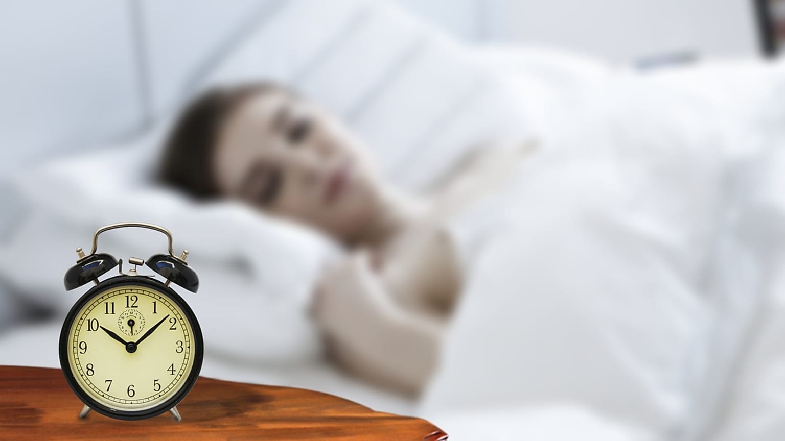 امرأة تنام والمنبه إلى جانبها 