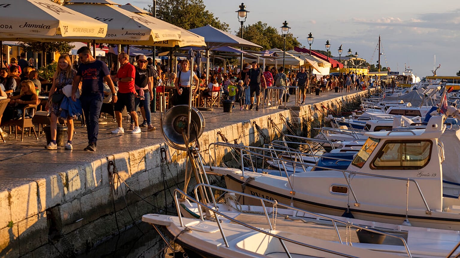 Holidaymakers walk by the harbor, in the Adriatic town of Rovinj, Croatia