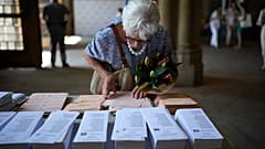 A woman holding a bouquet of flowers tries to select her ballots to vote at a polling station in Barcelona, Spain, Sunday July 23, 2023. 