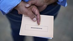 Ein Mann wartet vor einem Wahllokal in Madrid mit einem Wahlzettel in seiner Hand