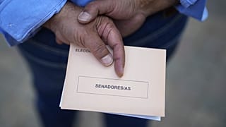 Ein Mann wartet vor einem Wahllokal in Madrid mit einem Wahlzettel in seiner Hand