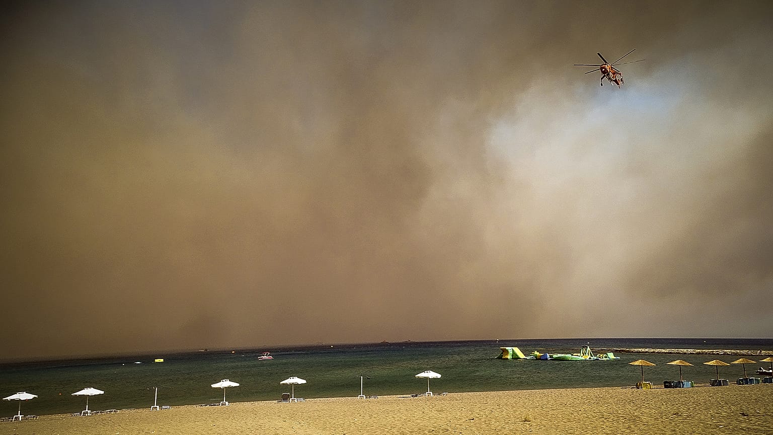 Tűzoltó helikopter egy kiürített rodoszi strand felett