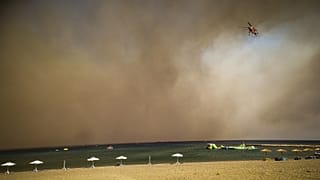 Tűzoltó helikopter egy kiürített rodoszi strand felett