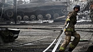 A Ukrainian firefighter works to extinguish a fire at a petrol station, July 2023.