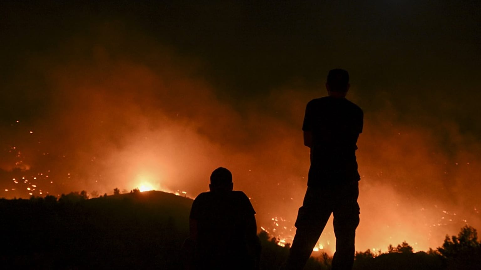 People watch the fires near the village of Malona in the Greek island of Rhodes on July 23, 2023.