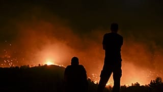 People watch the fires near the village of Malona in the Greek island of Rhodes on July 23, 2023.